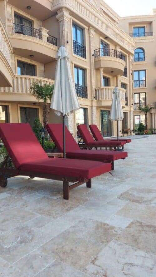 Poolside view of modern apartments at Aphrodite Park in Sunny Beach with sun loungers and umbrellas.