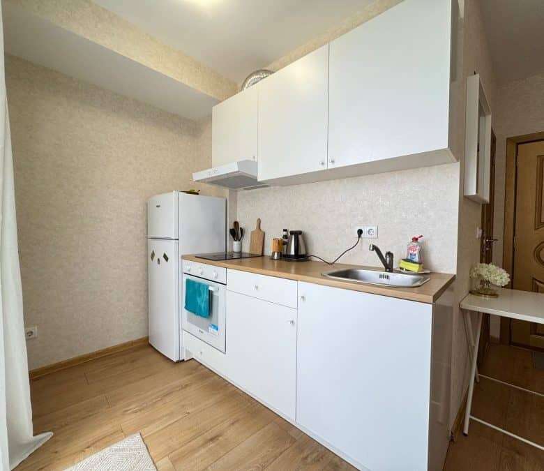 Modern fully furnished studio kitchen with white cabinets and appliances in Aphrodite Park, Sunny Be.