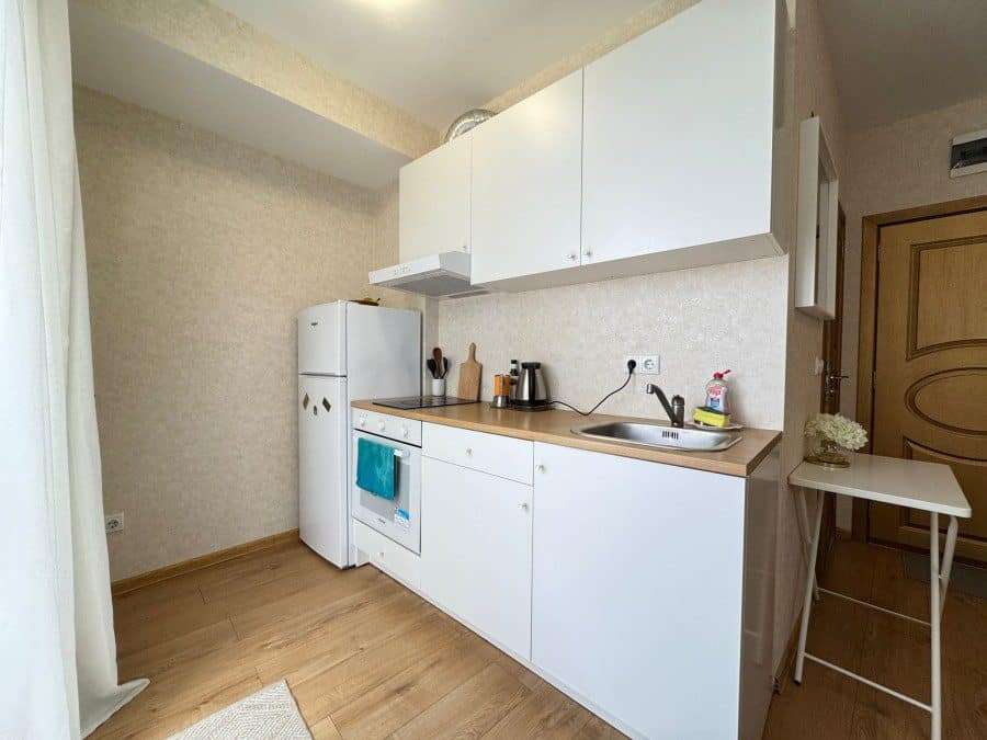 Modern fully furnished studio kitchen with white cabinets and appliances in Aphrodite Park, Sunny Be.