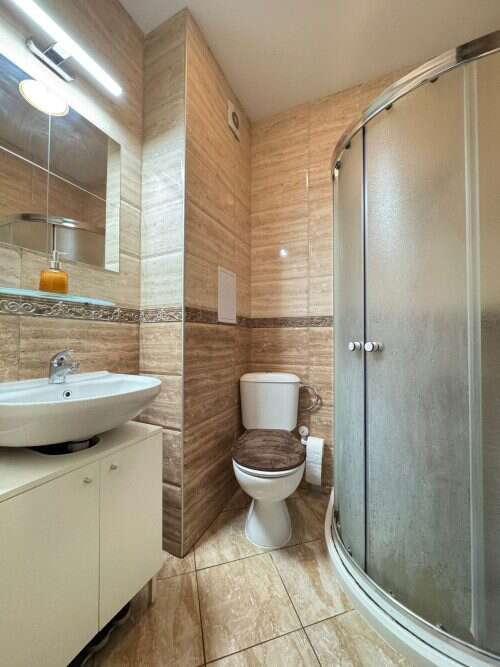 Bathroom with shower, toilet, and sink in a fully furnished studio apartment.