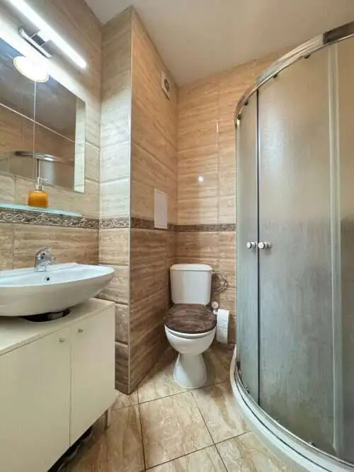 Bathroom with shower, toilet, and sink in a fully furnished studio apartment.
