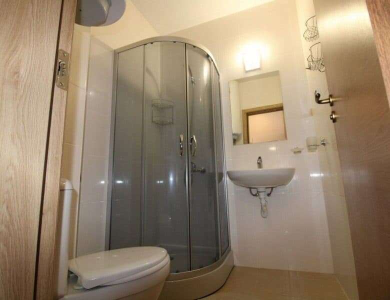 Small bathroom with shower, sink, and toilet in Sunny Day 6 studio apartment.