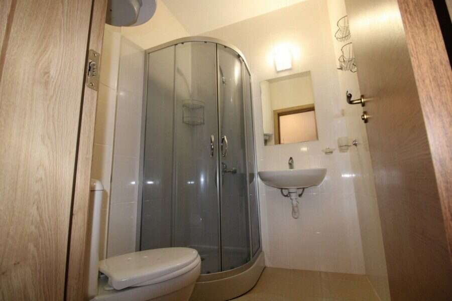 Small bathroom with shower, sink, and toilet in Sunny Day 6 studio apartment.