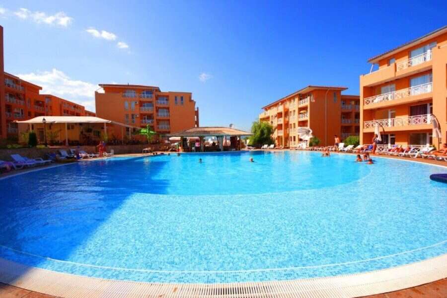 Pool area at Sunny Day 6 resort in Sunny Beach, Bulgaria, with orange apartment buildings and clear.