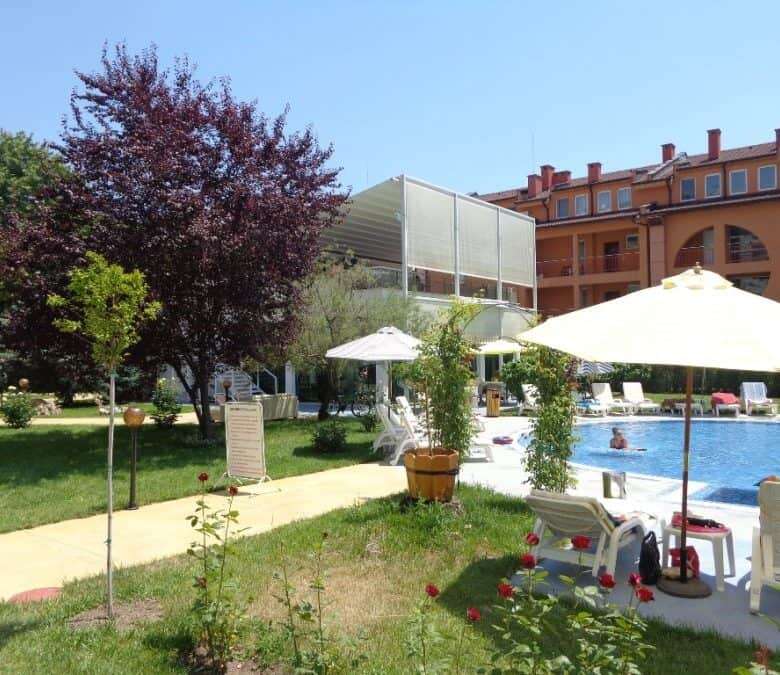 Poolside garden with lounge chairs, umbrellas, and lush greenery at Oasis, Ravda.