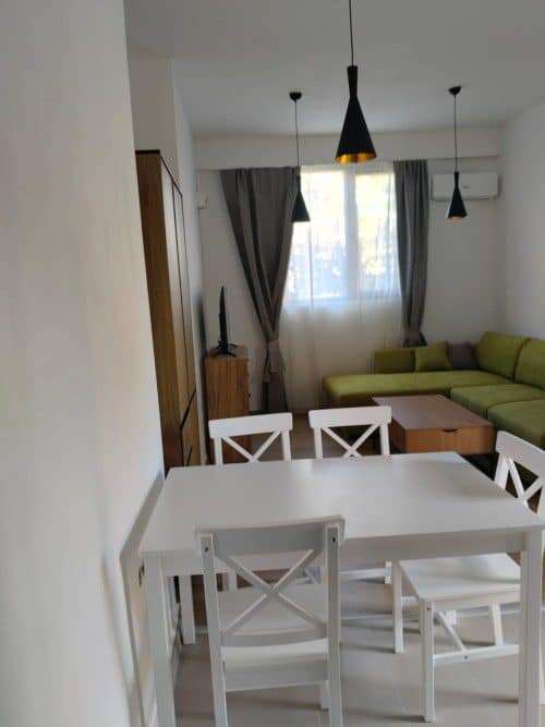 Bright living space with a dining area, sofa, and large window with curtains.