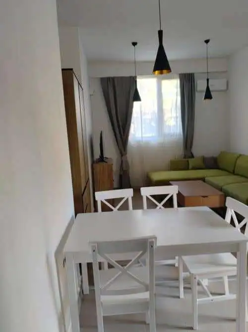Bright living space with a dining area, sofa, and large window with curtains.