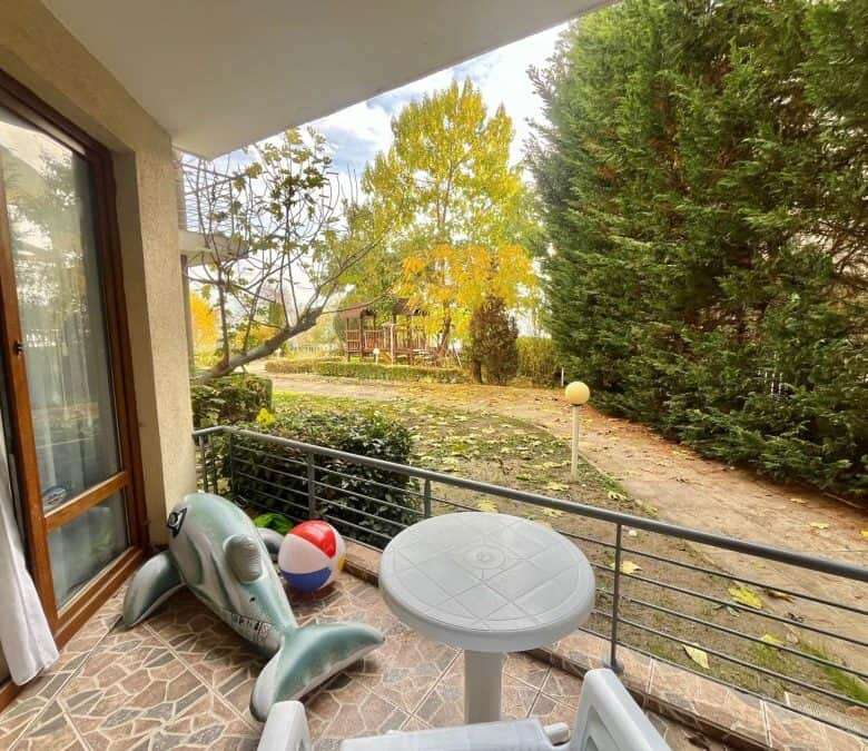 Sea view balcony with outdoor furniture overlooking lush greenery and trees.