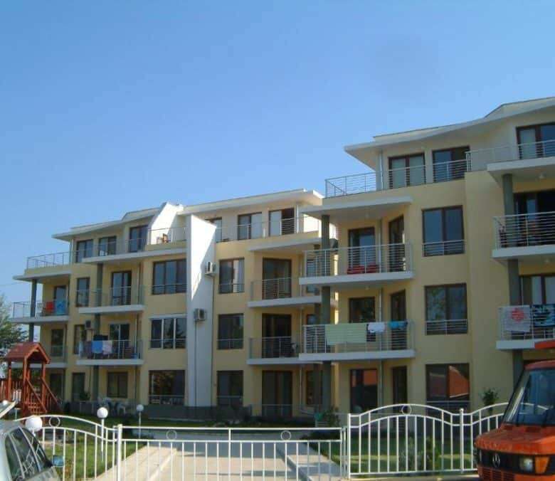 Bright, multi-story residential complex with balconies overlooking the sea.