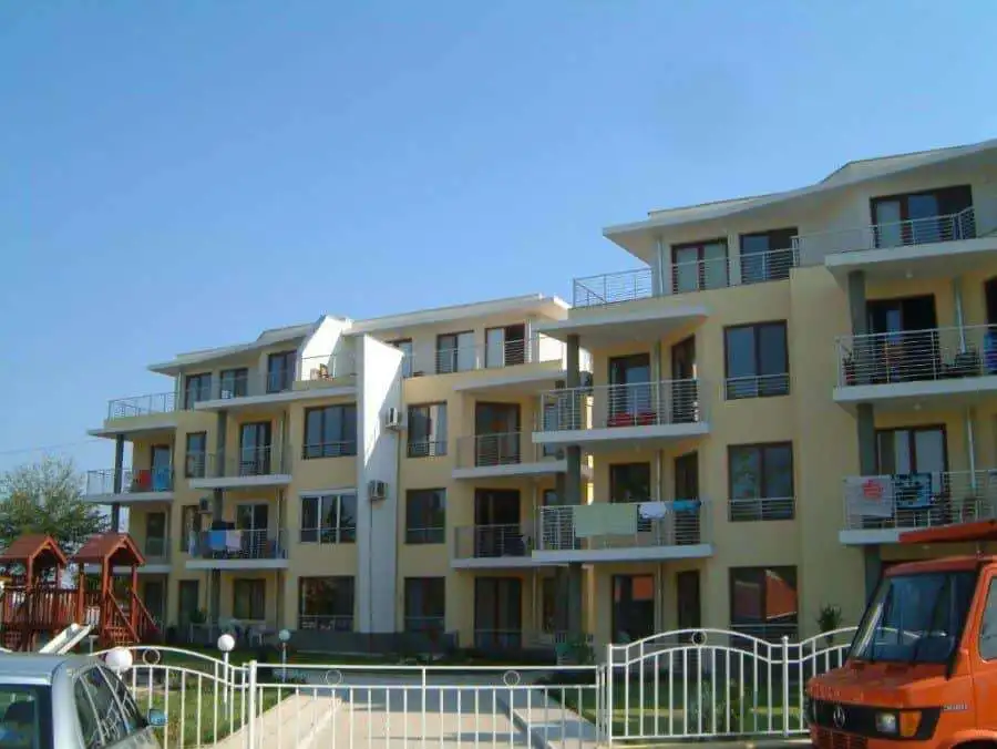 Bright, multi-story residential complex with balconies overlooking the sea.