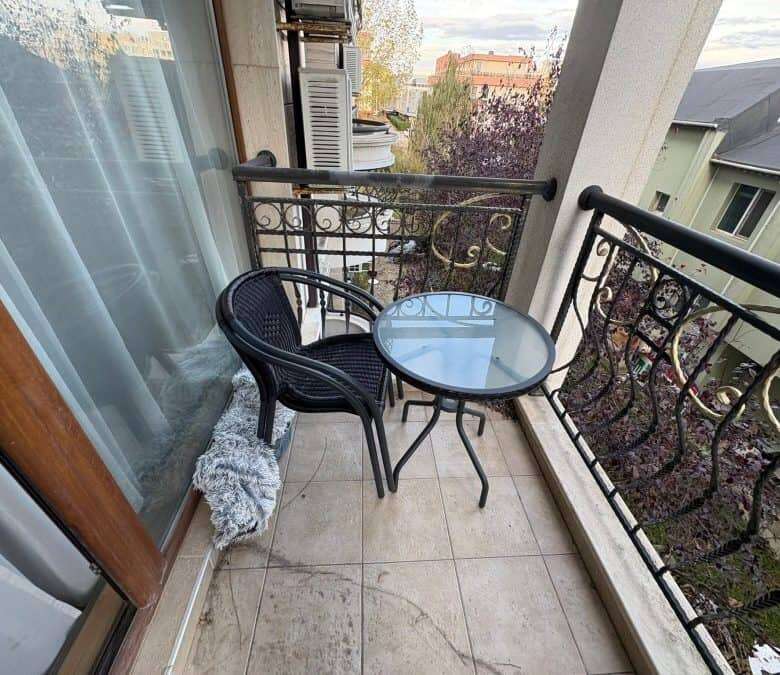 Balcony with black metal railing, glass table, and two chairs overlooking Sunny Beach. Perfect for r.