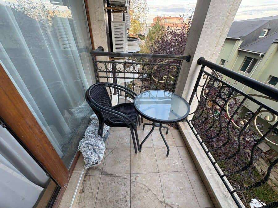Balcony with black metal railing, glass table, and two chairs overlooking Sunny Beach. Perfect for r.