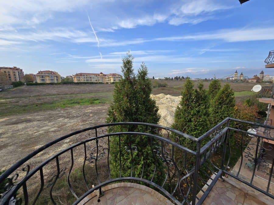 Modern apartment balcony with city and nature views in Ravda, Bulgaria. Balcony view of Ravda with trees, buildings, and blue sky.