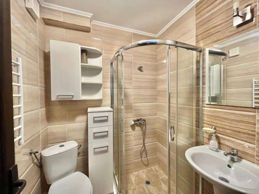 Modern bathroom with shower, toilet, and sink in Nessebar apartment. Bright bathroom with shower enclosure, toilet, and sink in a seaside apartment.