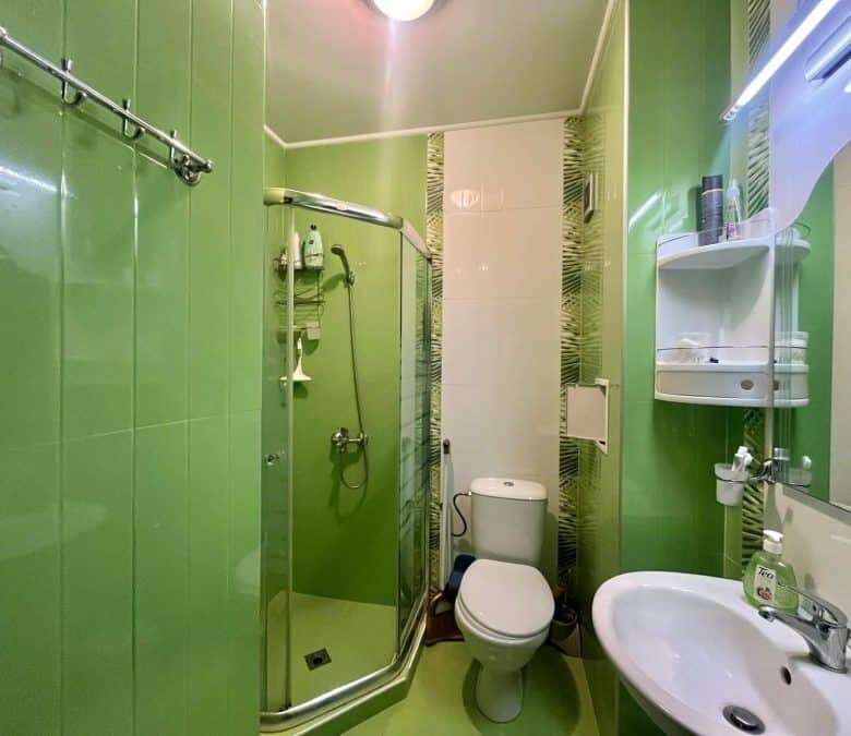 Green bathroom with shower, toilet, and sink in Odissey studio Nessebar.