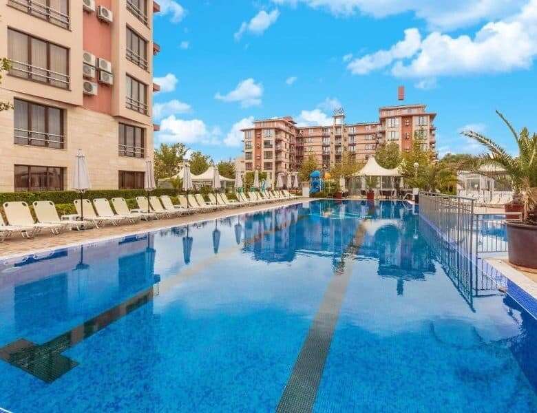 Pool with lounge chairs and surrounding greenery at Tarsis - Club & Spa.