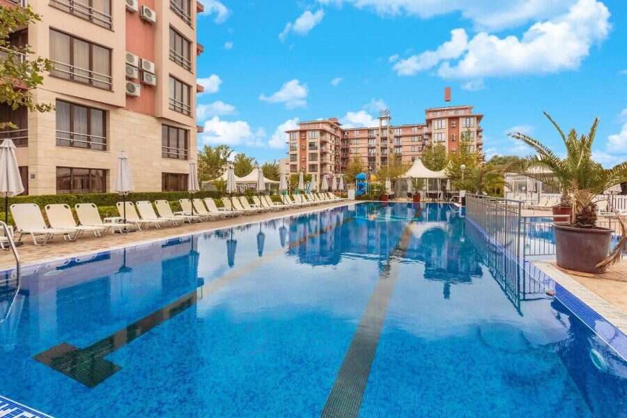 Pool with lounge chairs and surrounding greenery at Tarsis - Club & Spa.