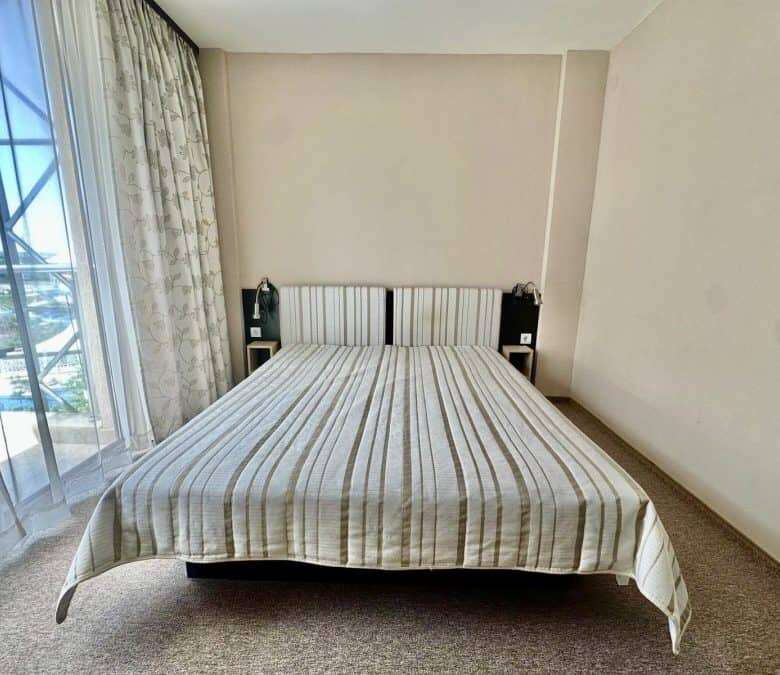 Bedroom with a large bed, striped bedding, and balcony view.