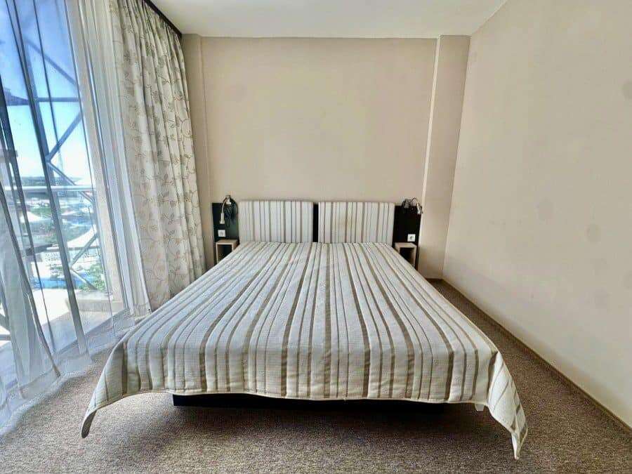 Bedroom with a large bed, striped bedding, and balcony view.