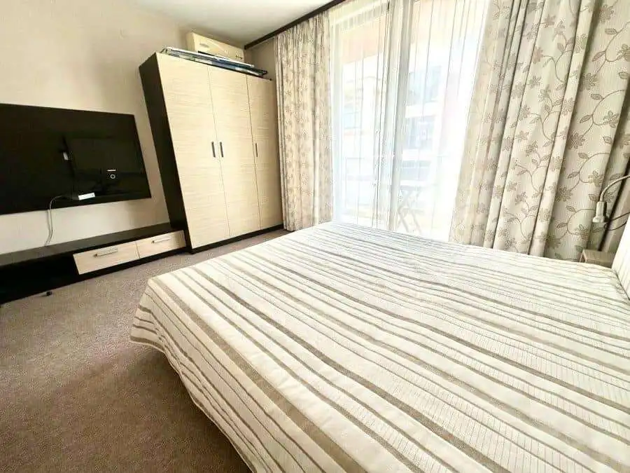 Modern bedroom with large window and wardrobe in Tarsis – Club & Spa. Spacious 2-bedroom, 2-bath apartment in Sunny Beach, 75 sq.m.