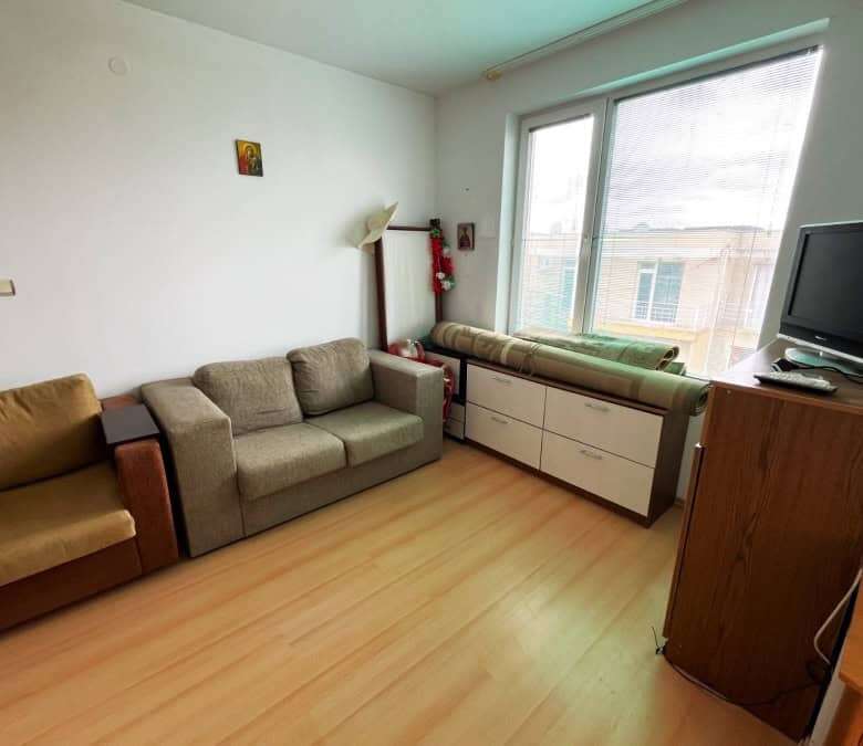 Bright living room with sofas, large window, and TV in Sunny Day 5 apartment.