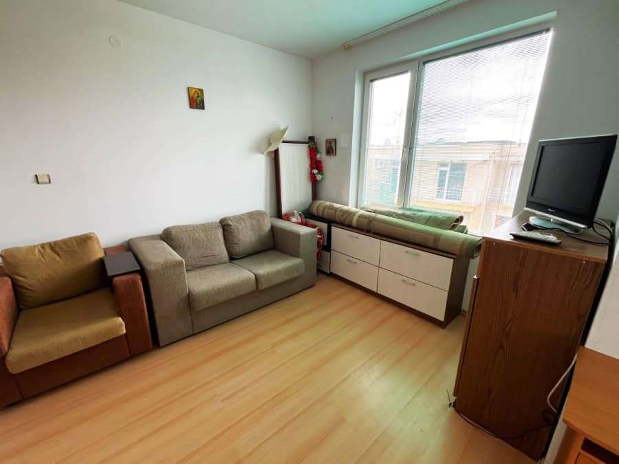 Bright living room with sofas, large window, and TV in Sunny Day 5 apartment.
