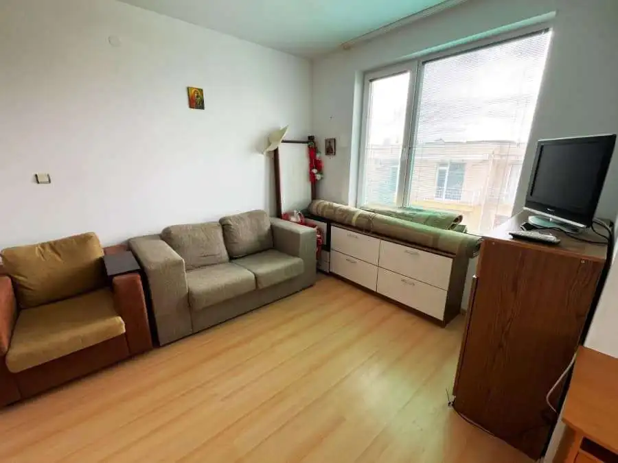 Cozy Furnished Apartment in Sunny Day 5 Bright living room with sofas, large window, and TV in Sunny Day 5 apartment.
