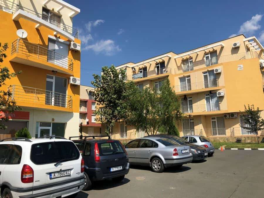 Bright yellow apartment complex with multiple balconies and parking area.
