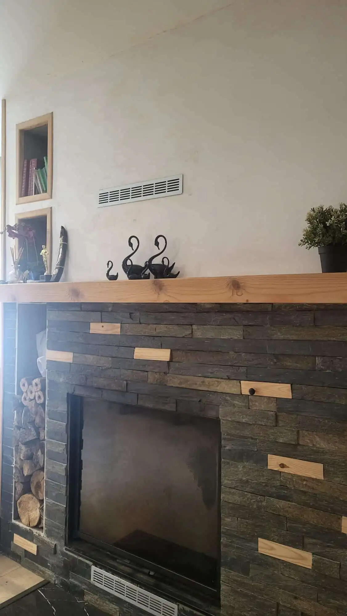 Modern fireplace with a sleek black finish and stylish wooden accents in a contemporary living space.
