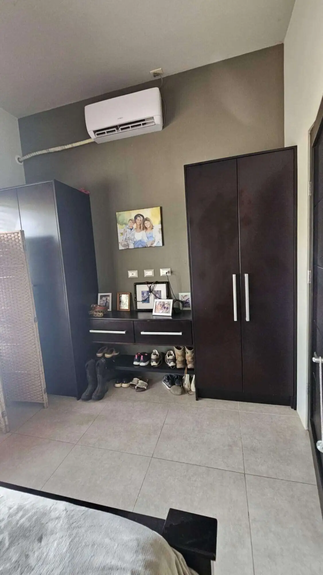 Spacious bedroom featuring a sleek wardrobe, air conditioner, and decorative wall art.