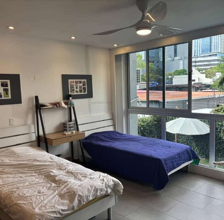 Modern bedroom with large windows and city views in Panama City luxury apartments.