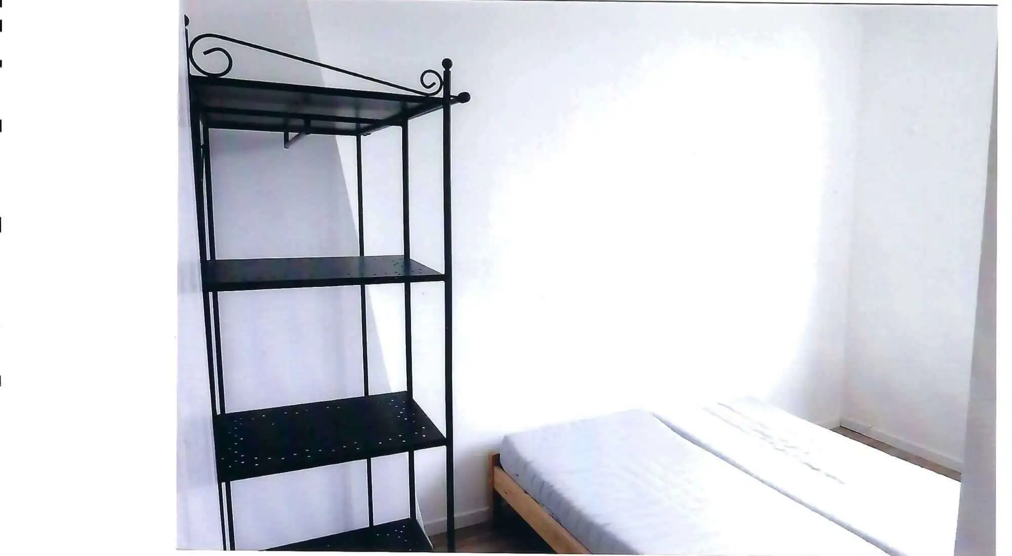 Interior view of a bedroom in a seaside house with a metal shelf and a bed in Mers Les Bains.