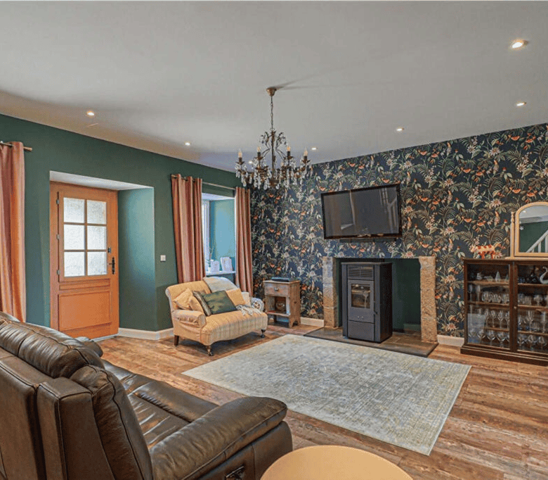 Spacious living area in a Brittany gite with colorful walls, elegant chandelier, and cozy furniture.