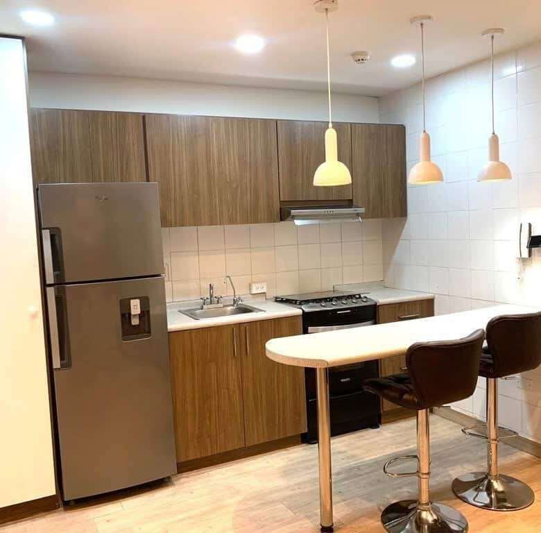 Modern kitchen with stainless steel refrigerator and stylish pendant lighting in Panama City luxury.