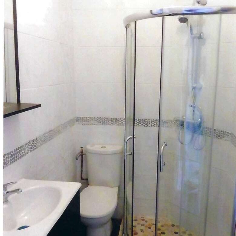 Bright bathroom with shower, toilet, and sink in seaside property.