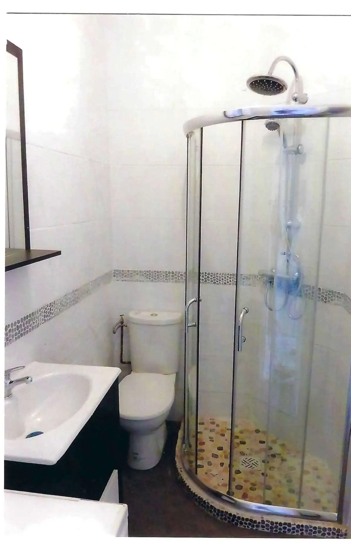 Bright bathroom with shower, toilet, and sink in seaside property.