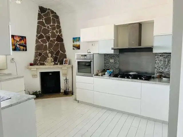 Spacious kitchen in a charming Sardinian home with modern appliances and cozy fireplace.