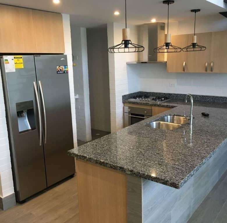 Bright, contemporary kitchen featuring a refrigerator, sink, and stylish lighting fixtures.
