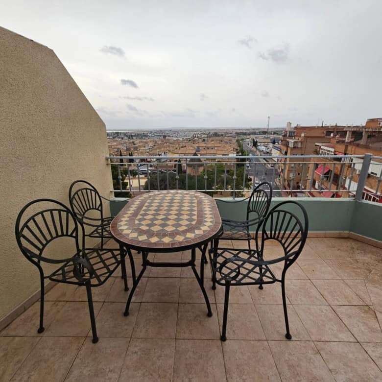 Spacious balcony with outdoor dining area overlooking the cityscape of Torrevieja.