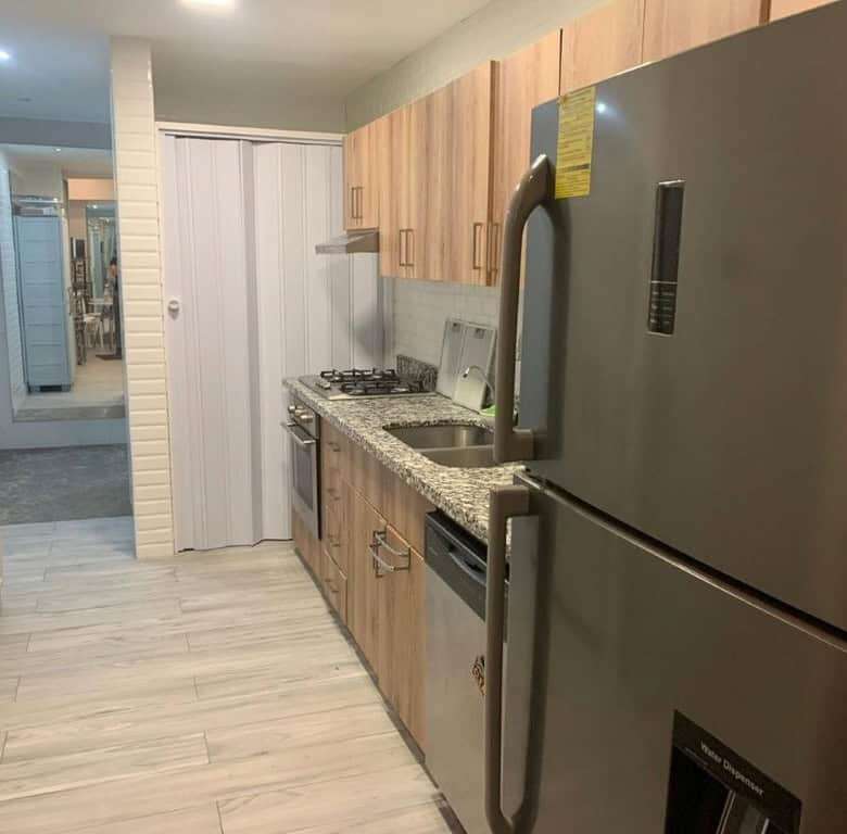 Contemporary kitchen with wooden cabinets and stainless steel appliances in Panama City luxury apart.