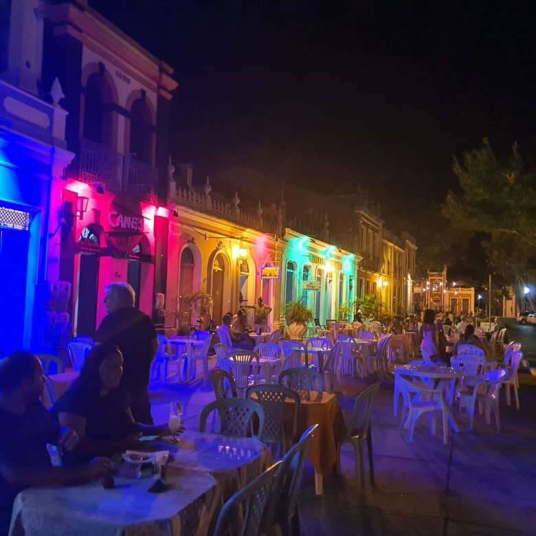 Brightly lit colonial houses in Bahia with outdoor dining area at night.