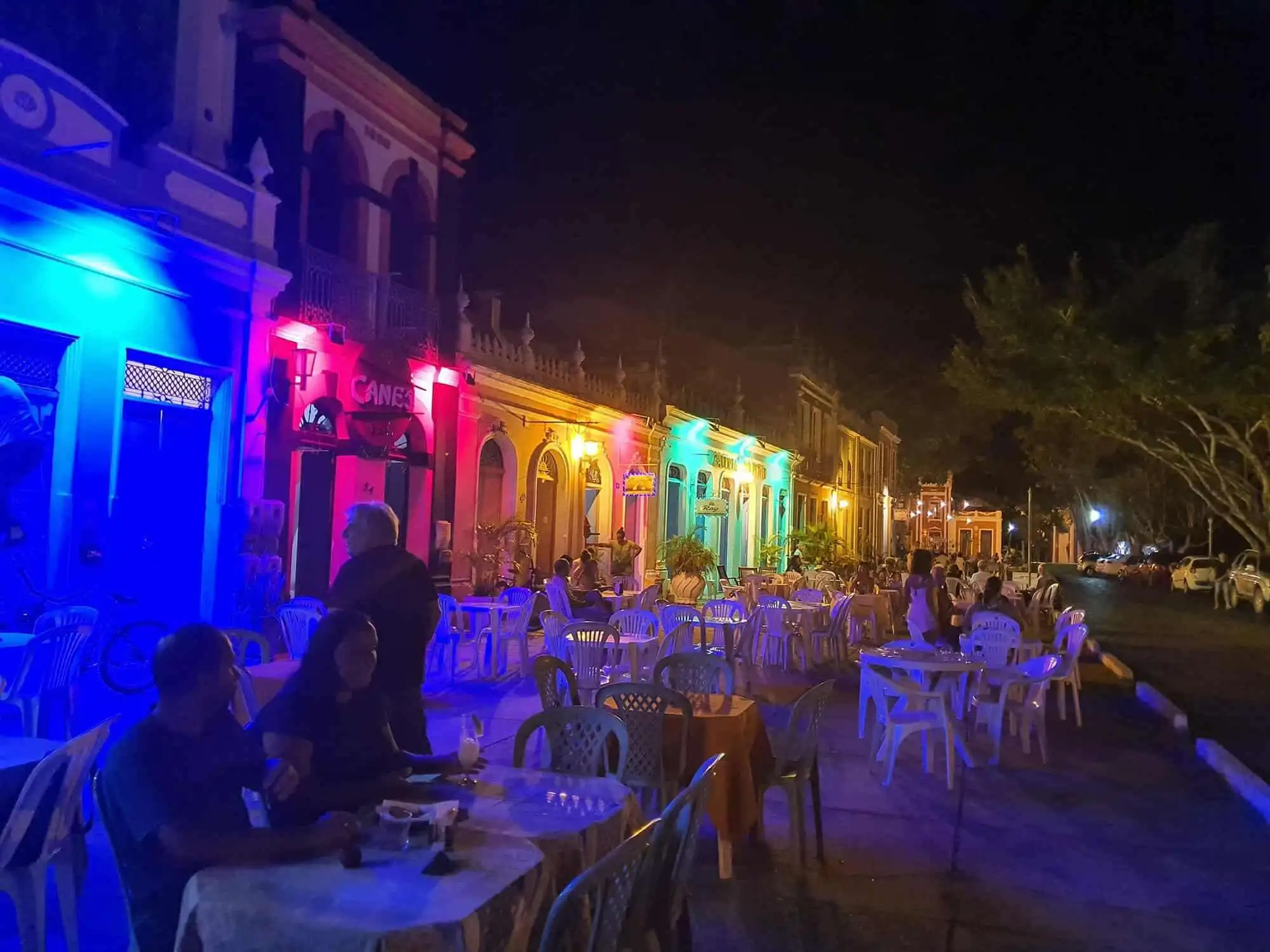 Brightly lit colonial houses in Bahia with outdoor dining area at night.