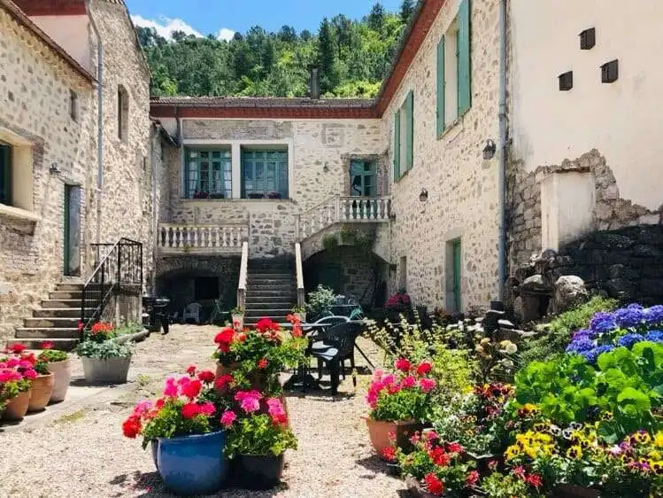 Elegant estate courtyard with colorful flowers and historic stone buildings.