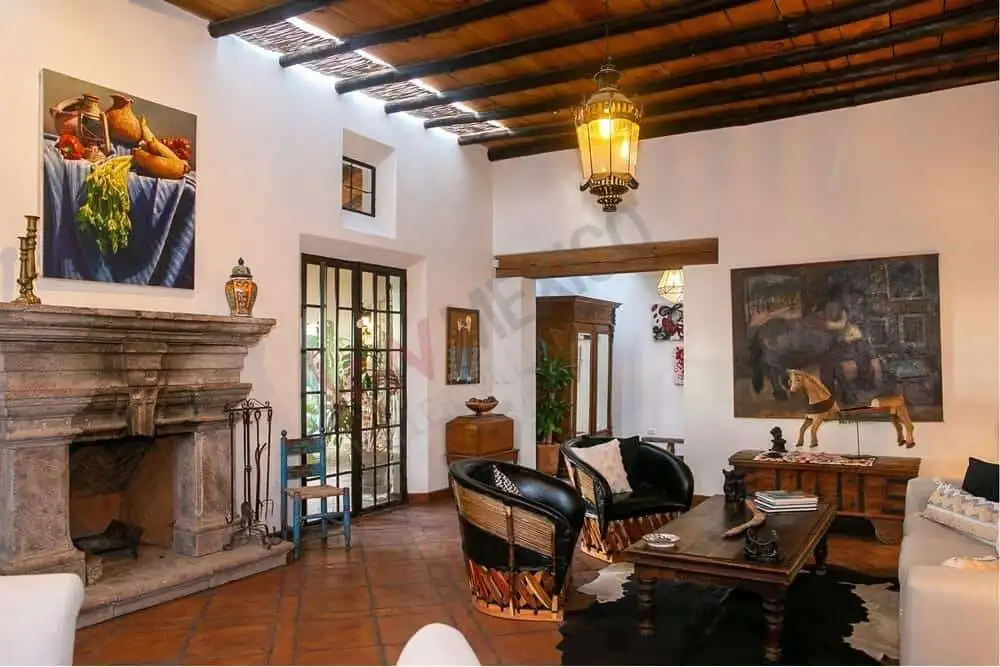 Elegant Colonial Living Room with Rustic Decor and Artworks Style living room featuring wooden beams, vintage furniture, and vibrant artwork.