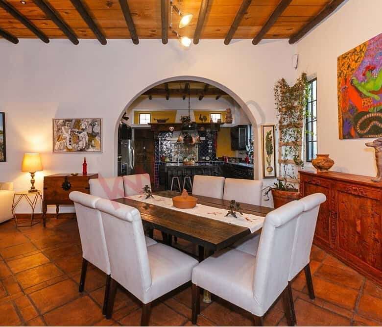 Spacious interior featuring a wooden dining table, white chairs, and colorful art pieces.