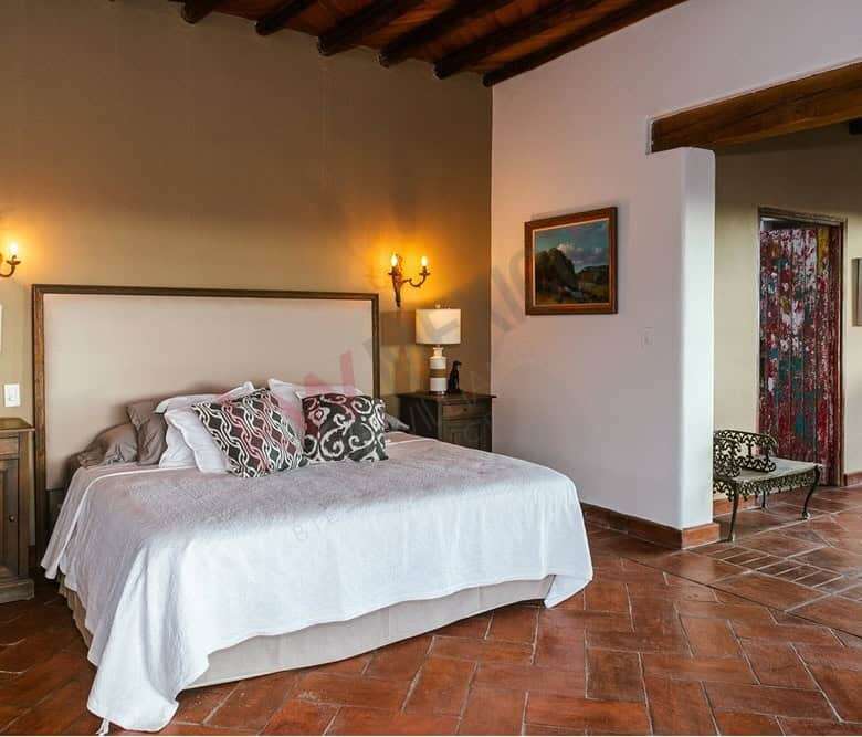 Elegant bedroom with rustic wooden beams and terracotta tile flooring.