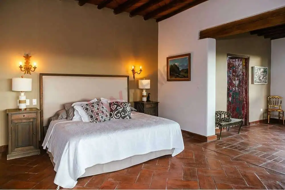 Cozy Bedroom in Colonial Estate Elegant bedroom with rustic wooden beams and terracotta tile flooring.