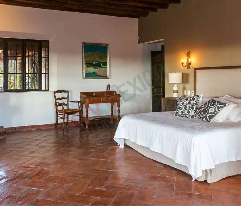 Spacious bedroom in colonial estate with dam views and rustic decor.