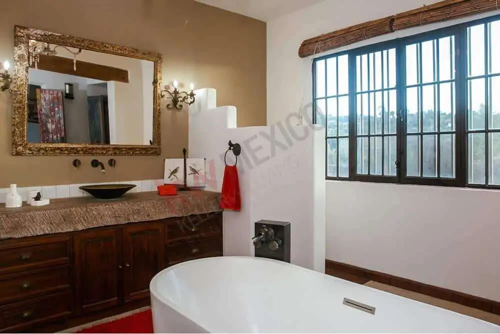 Elegant bathroom with large window and rustic decor Spacious bathroom featuring a large window with scenic views, a stylish vanity, and a modern bathtub.