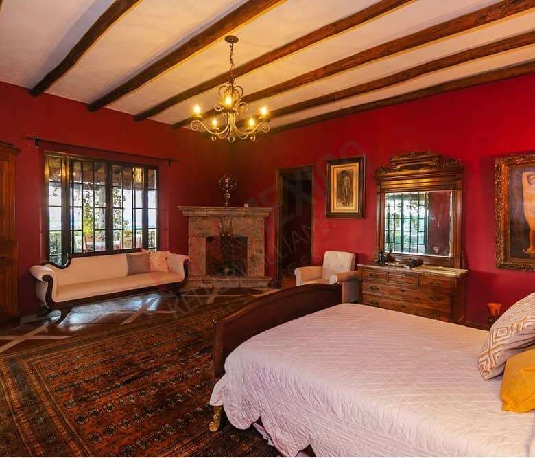 Elegant colonial bedroom with vintage decor and large windows overlooking Allende Dam.